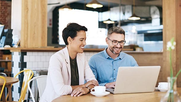 male and female at coffee shop looking at laptop
